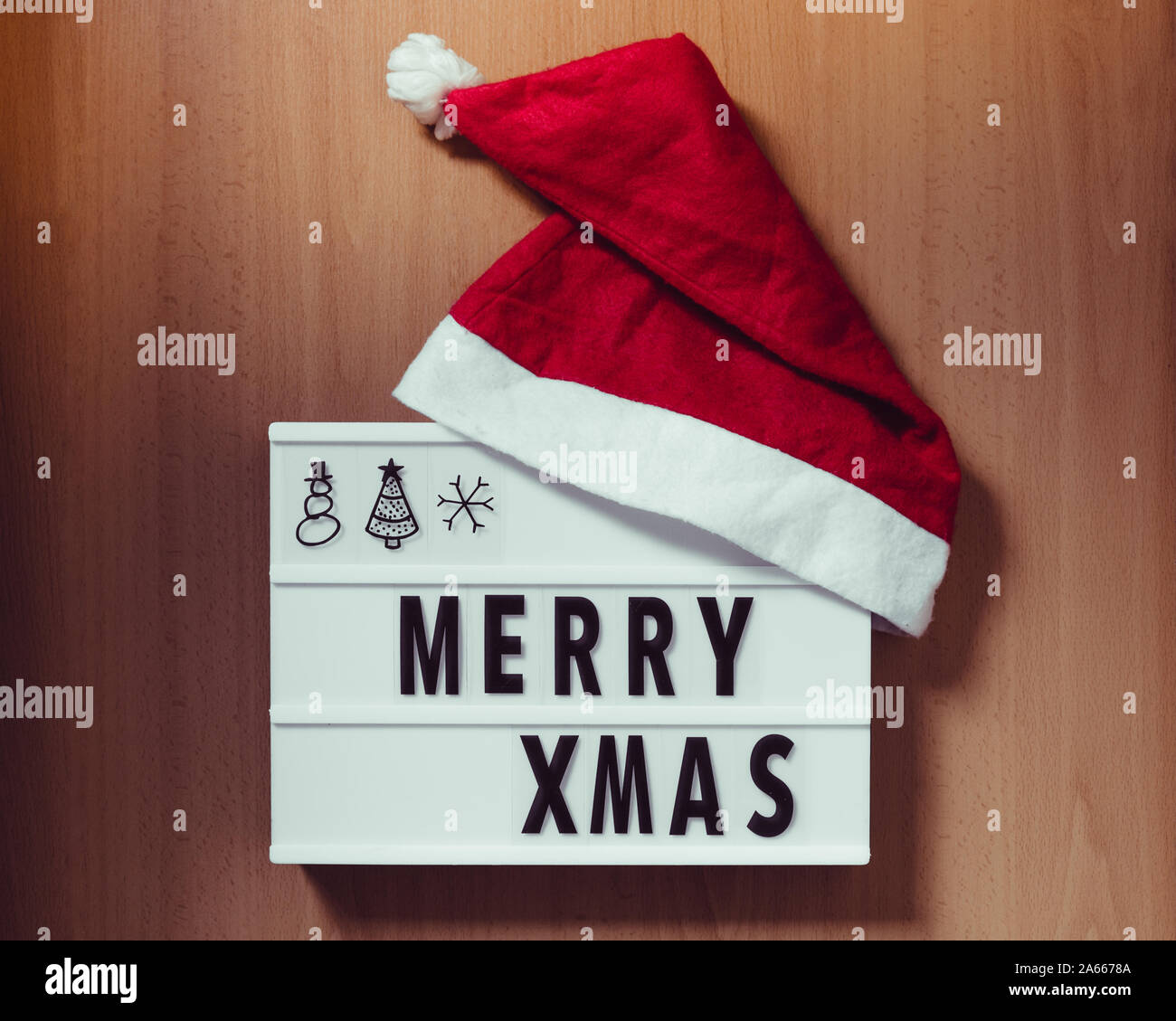 Lightbox avec les mots 'merry Xmas' et rouge santa hat sur fond de bois Banque D'Images