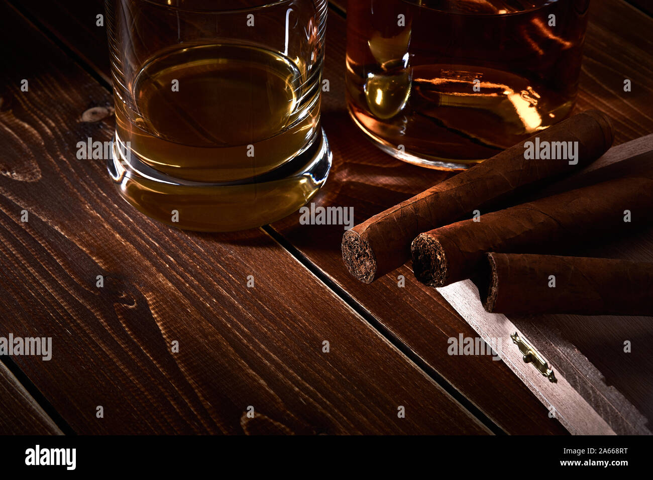 Nature morte avec verre et bouteille d'alcool, de whisky ou de brandy ou de rhum. Trois cigares cubains dans une boîte en bois avec de l'espace pour le texte. Banque D'Images