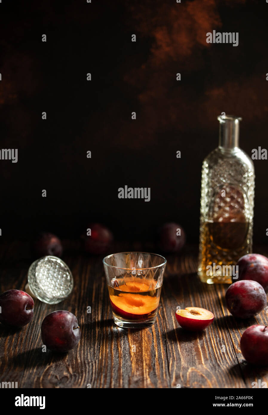 Rakia ou traditionnels de fruits brandy rakija des Balkans. Eau-de-vie de prune sljivovica dans un verre et la carafe sur une table en bois et un arrière-plan sombre. La verticale Banque D'Images