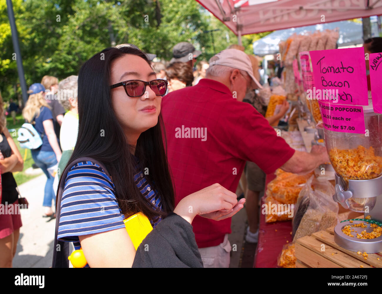 Madison, WI USA. Jul 2018. Asian American teen appréciant les variétés de maïs soufflé à saveur de Wisconsin à un marché agricole. Banque D'Images