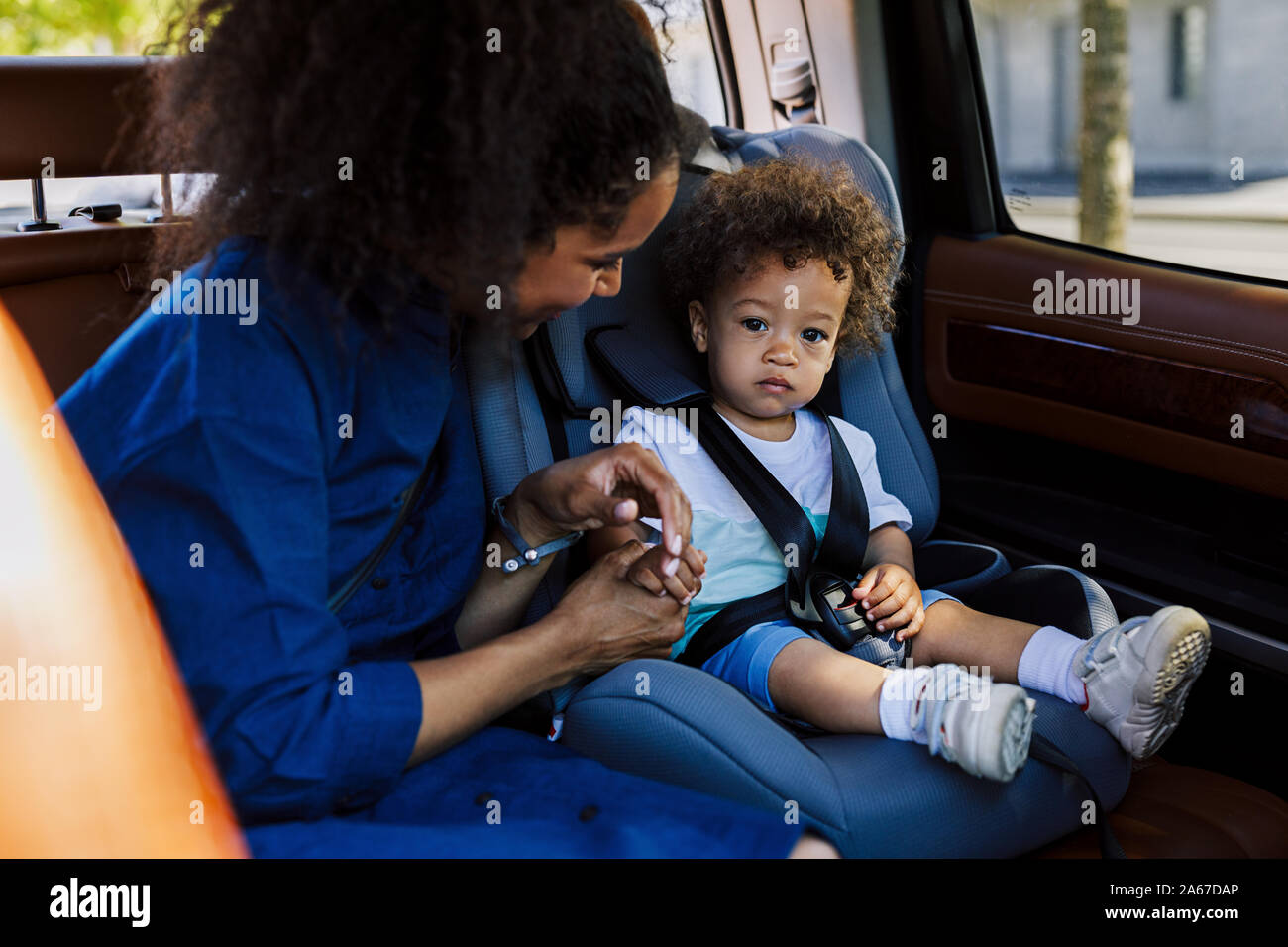 Jeune mère qui tient la main de son fils assis sur le siège arrière d'une voiture Banque D'Images