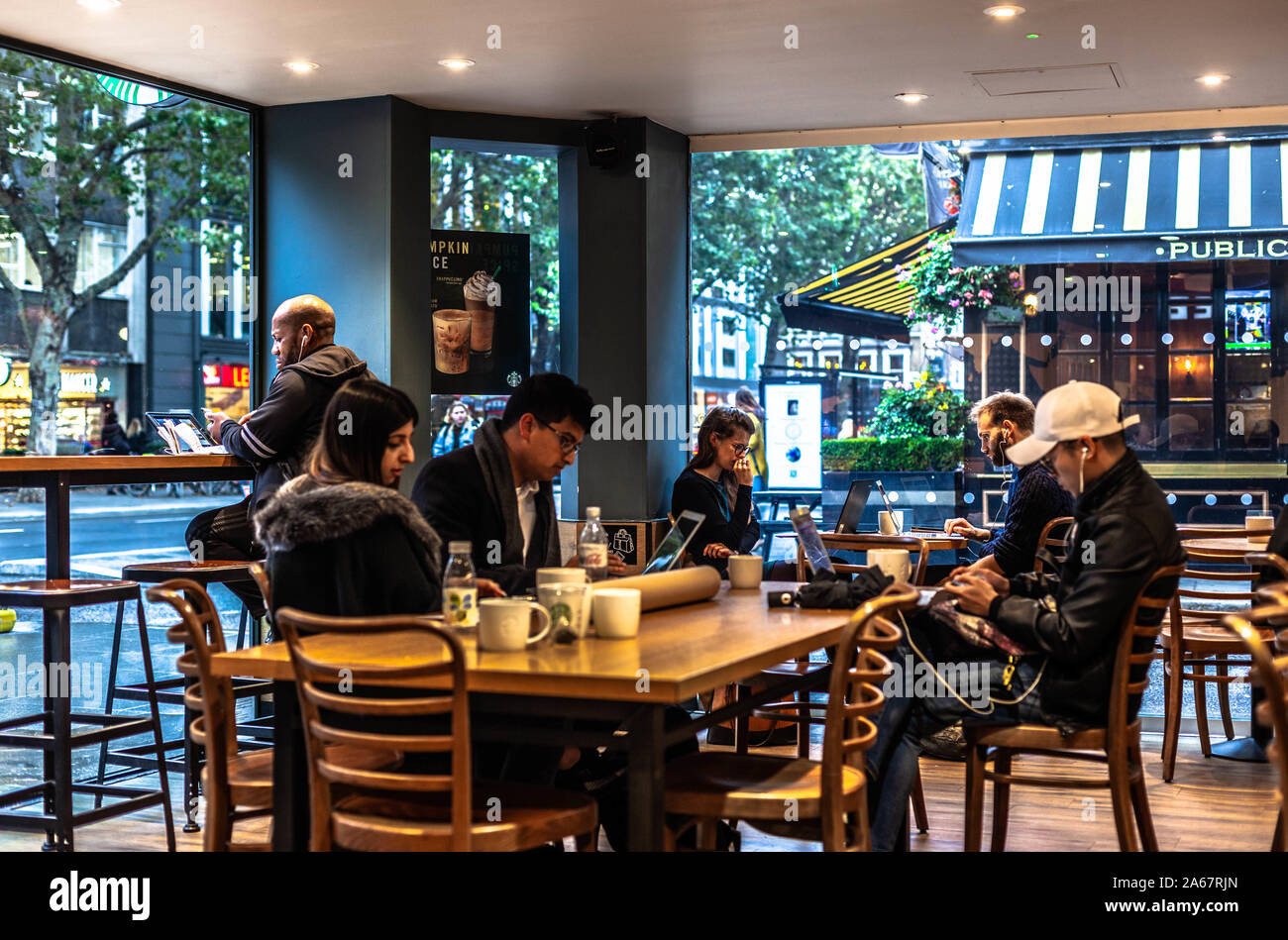 Groupe multiculturel de personnes utilisant des ordinateurs portables à l'intérieur d'un café Starbucks, Londres, Angleterre, Royaume-Uni. Banque D'Images