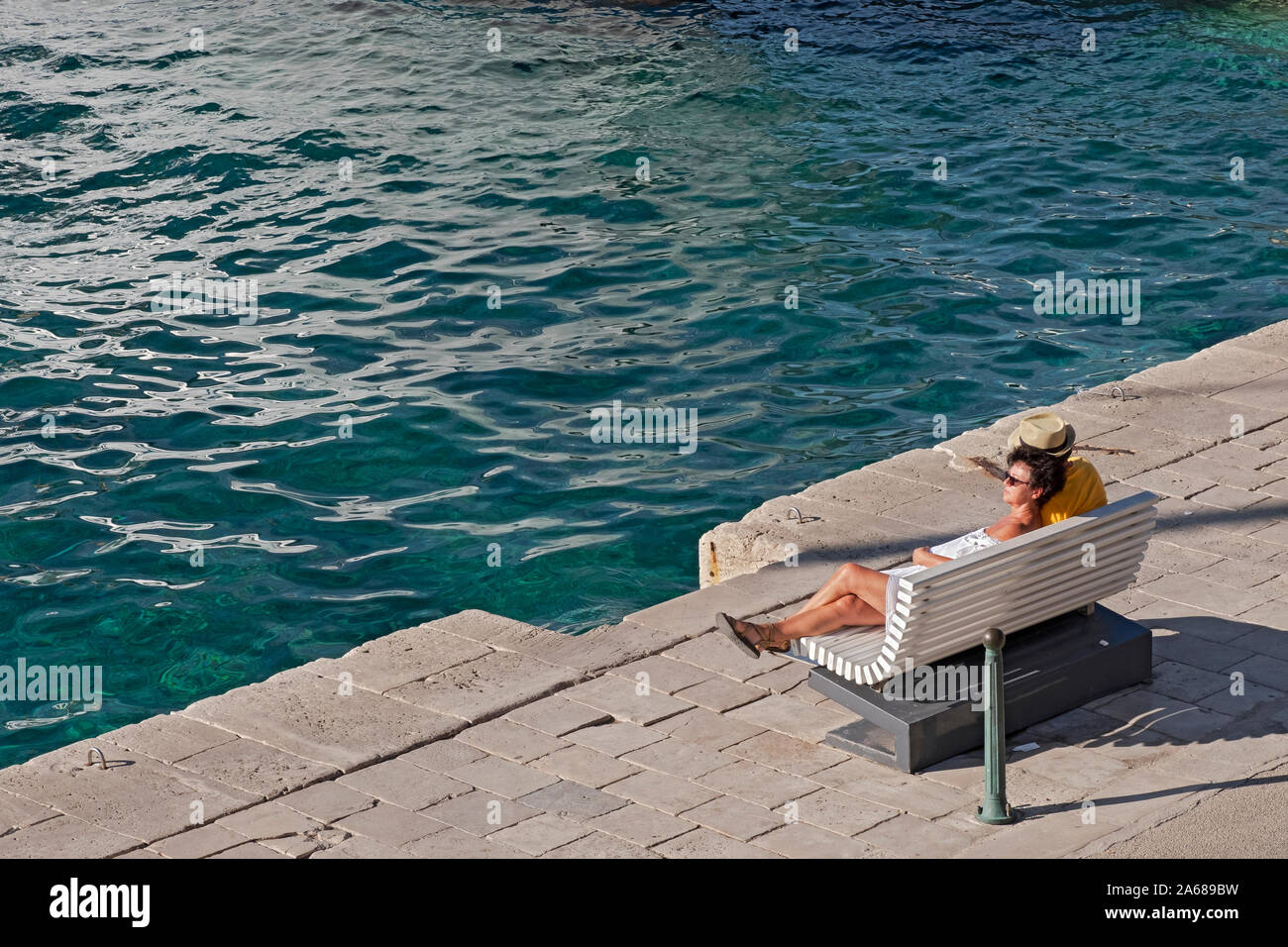 Un couple d'âge moyen, probablement marié, se détendre seul dans ses pensées, sur un banc à la côte adriatique croate dans l'île de Korcula. Banque D'Images