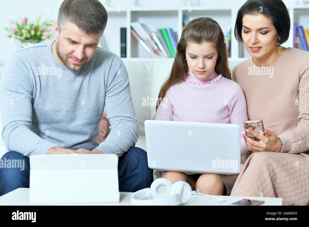 Heureux parents et sa fille à l'aide d'appareils numériques Banque D'Images
