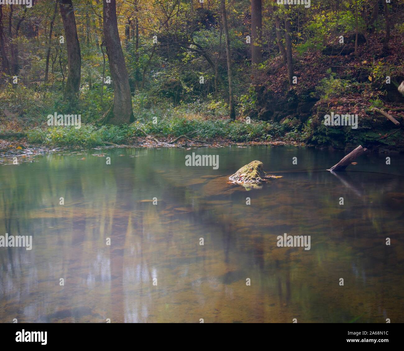 L'eau claire sans une seule feuille à l'automne sur une rivière. Formation rocheuse culminant visible hors de l'eau. Arbre mort ci-dessus de l'eau. Un calme Banque D'Images