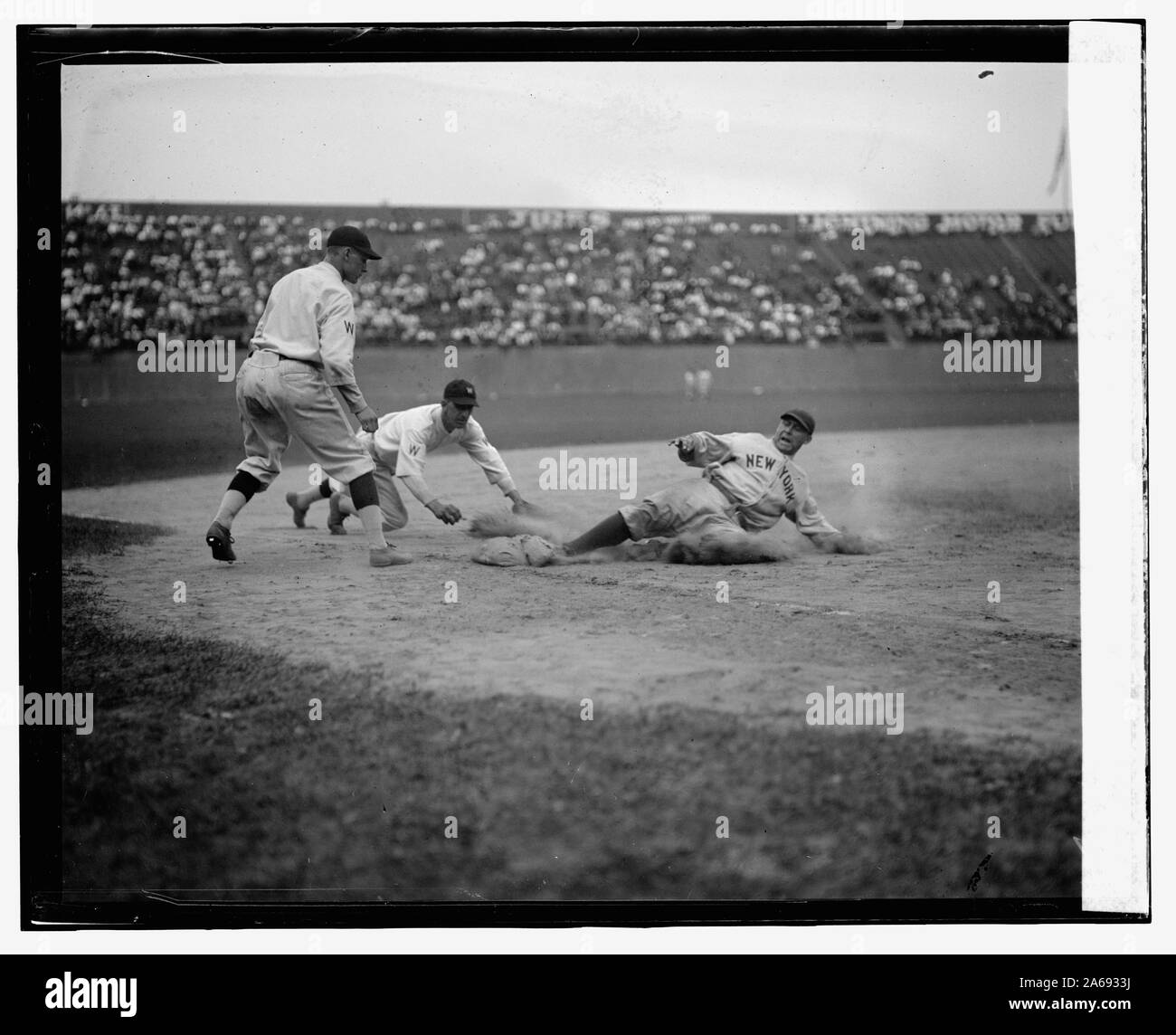 Yankee catcher Wally Schang glisse en toute sécurité dans 3e base en deuxième partie. Sénateurs 3e but est Ossie Bluege et pitcher de la sauvegarde de jeu est Firpo Marberry. Sénateurs gagné 2e match 7-2 (baseball) Banque D'Images