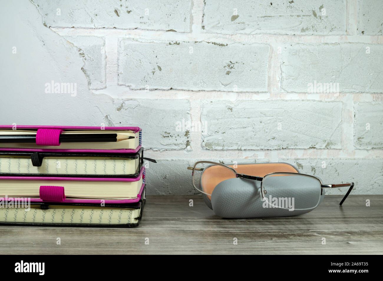 Retour à l'école concept avec pile de livres et lunettes de lecture contre un mur en brique blanche avec copie espace libre Banque D'Images