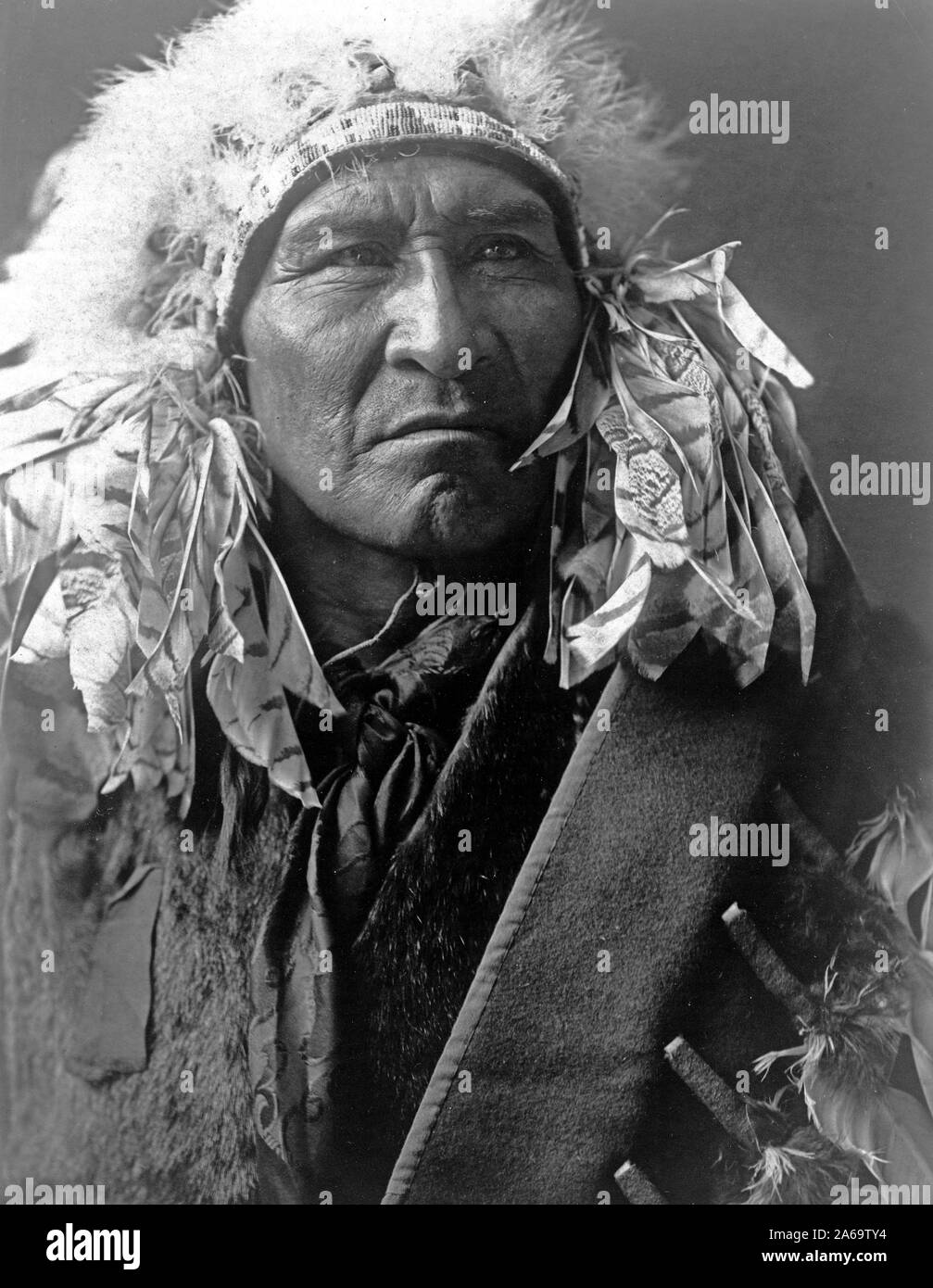 Edward S. Curits les Indiens - photo présente le pain, un Indien Apsaroke, portant une coiffe ca. 1908 Banque D'Images Edward S. Curits les Indiens - photo présente le pain, un Indien Apsaroke, portant une coiffe ca. 1908 Banque D'Images