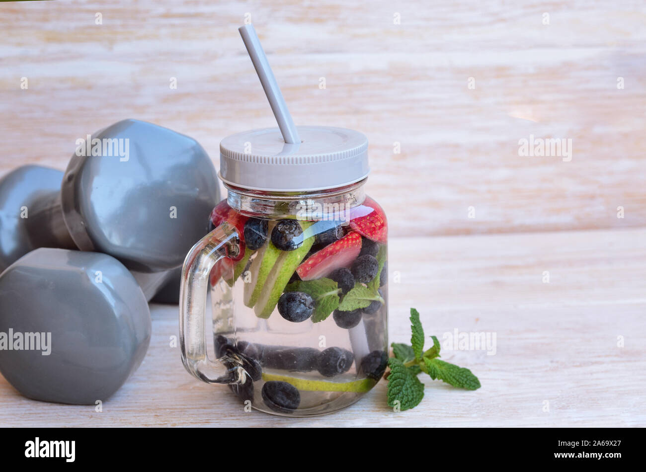 Detox eau infusée en pot Mason et deux haltères gris. Bien manger et l'exercice concept. Arrière-plan de vie sain avec l'exemplaire de l'espace. Banque D'Images