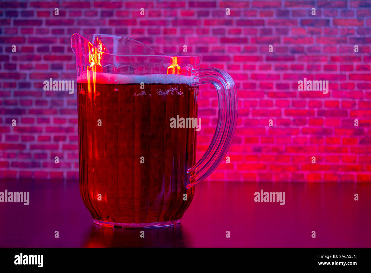 Pichet de bière sur un fond de brique rouge avec éclairage Banque D'Images
