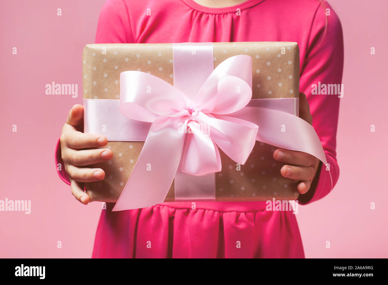 Cadeaux de luxe dans girl's hands sur le fond rose. Arc parfait. Concept de la nouvelle année, Noël, Saint Valentin, cadeaux Banque D'Images