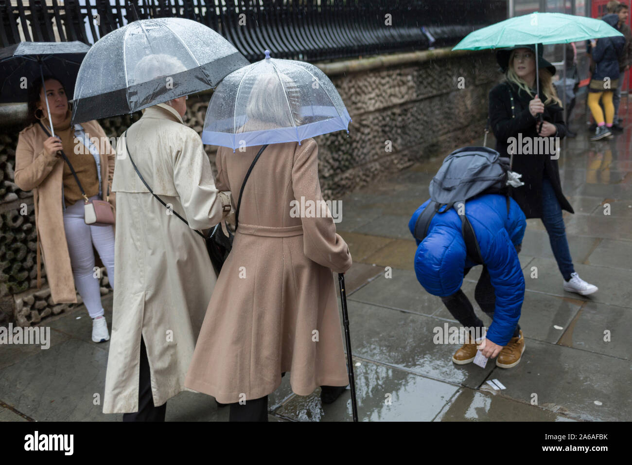 Utiliser deux dames parapluies transparents lors de fortes pluies sur une après-midi d'automne à l'extérieur de St. Martin-dans-le-champs église sur Trafalgar Square, le 24 octobre 2019, à Westminster, Londres, Angleterre. Banque D'Images