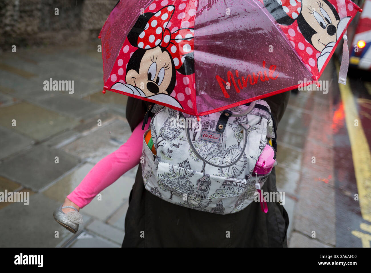 Une mère porte son enfant sous un parapluie Minnie Mouse au cours de fortes  pluies sur une après-midi d'automne près de Trafalgar Square, le 24 octobre  2019, à Westminster, Londres, Angleterre Photo