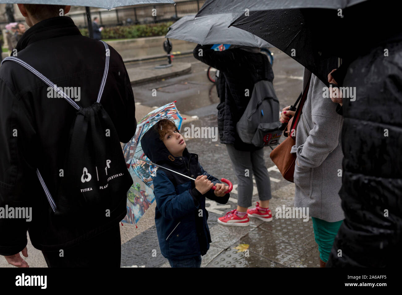 Un jeune visiteur de la capitale supporte de fortes pluies sur une après-midi d'automne à l'extérieur de St. Martin-dans-le-champs église sur Trafalgar Square, le 24 octobre 2019, à Westminster, Londres, Angleterre. Banque D'Images
