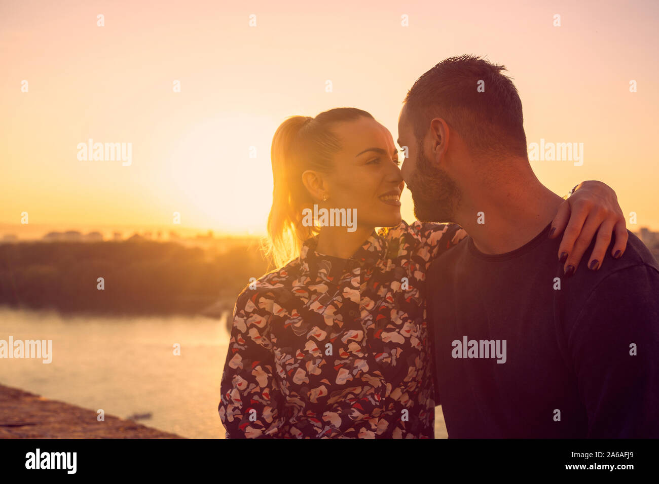 Smiling young man and woman accolades et embrassades au coucher du soleil Banque D'Images