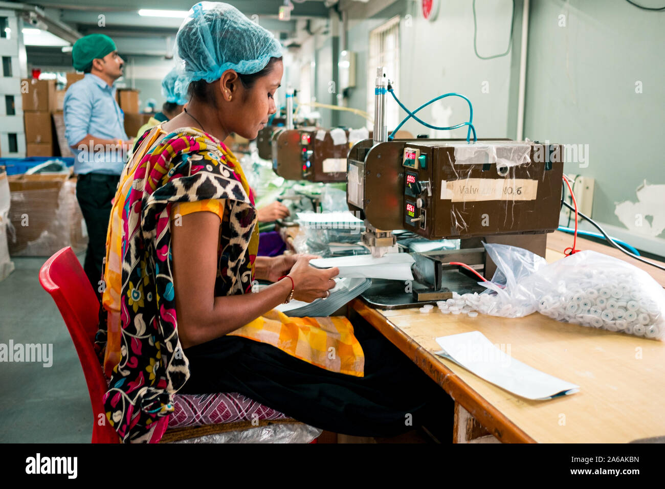 New Delhi, Inde - 10 septembre 2019 : une femme indienne au travail à l'aide de l'équipement industriel à l'intérieur de l'usine de fabrication d'emballage avec l'expression sereine Banque D'Images