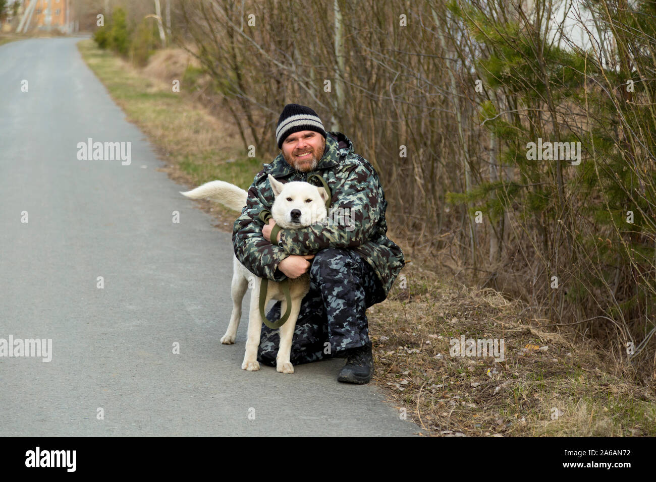 Un homme en salopette pour une promenade avec un chien Banque D'Images