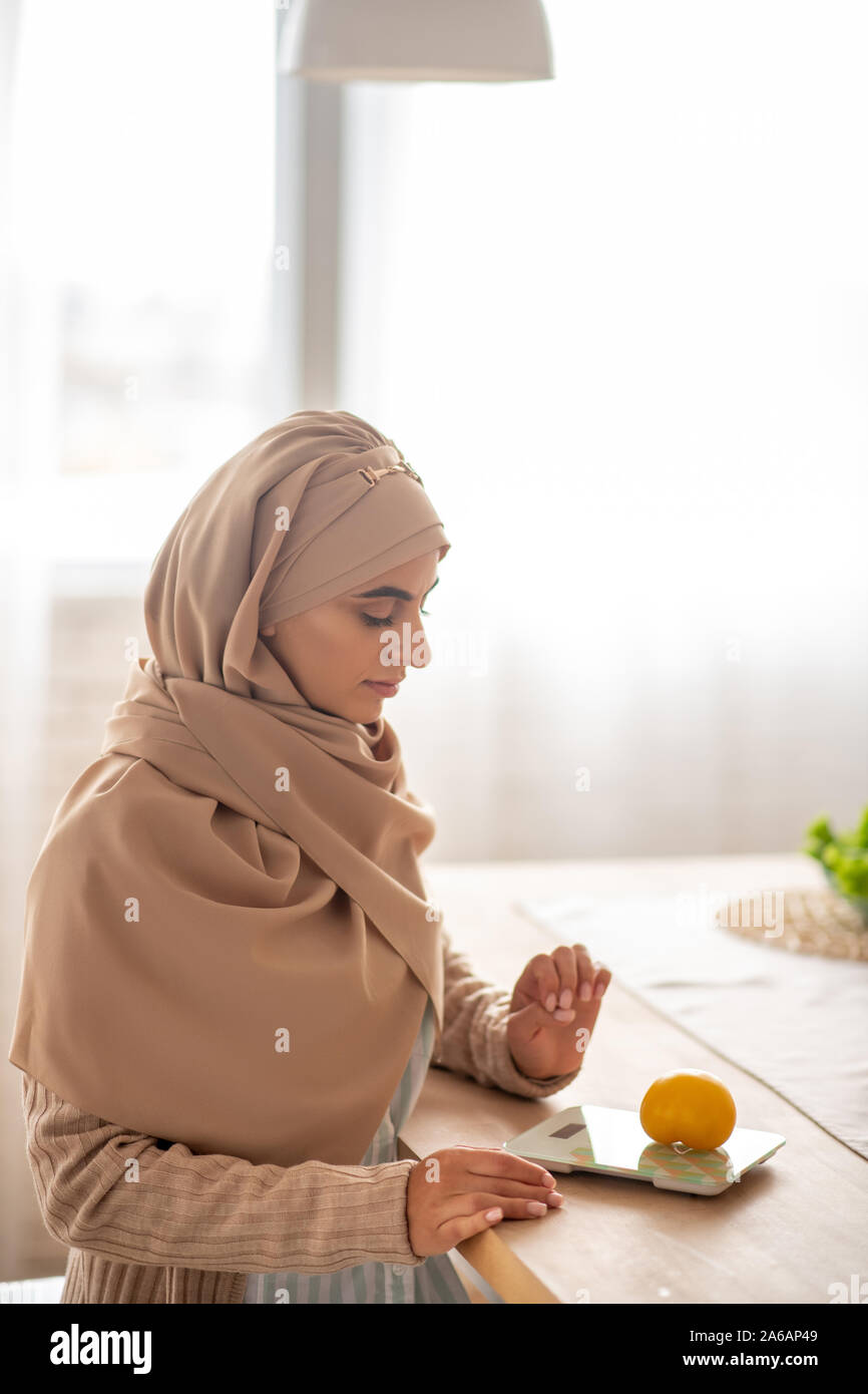 Jeune musulmane faisant mesurer l'alimentation Banque D'Images