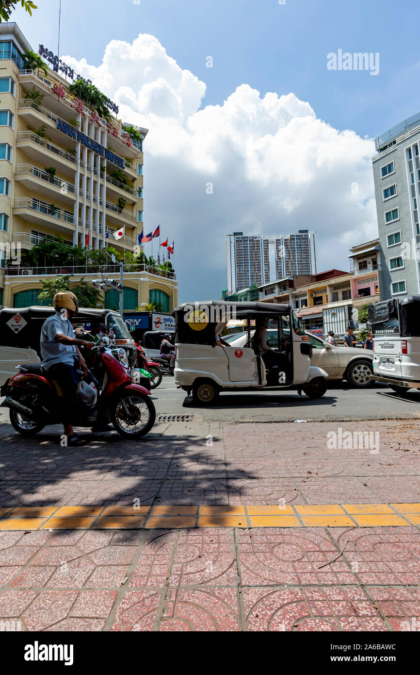 Les personnes conduisant des motos & Équitation dans Col App des taxis sont disponibles pour un feu de circulation passe au vert sur Monivong Blvd. à Phnom Penh, Cambodge. Banque D'Images