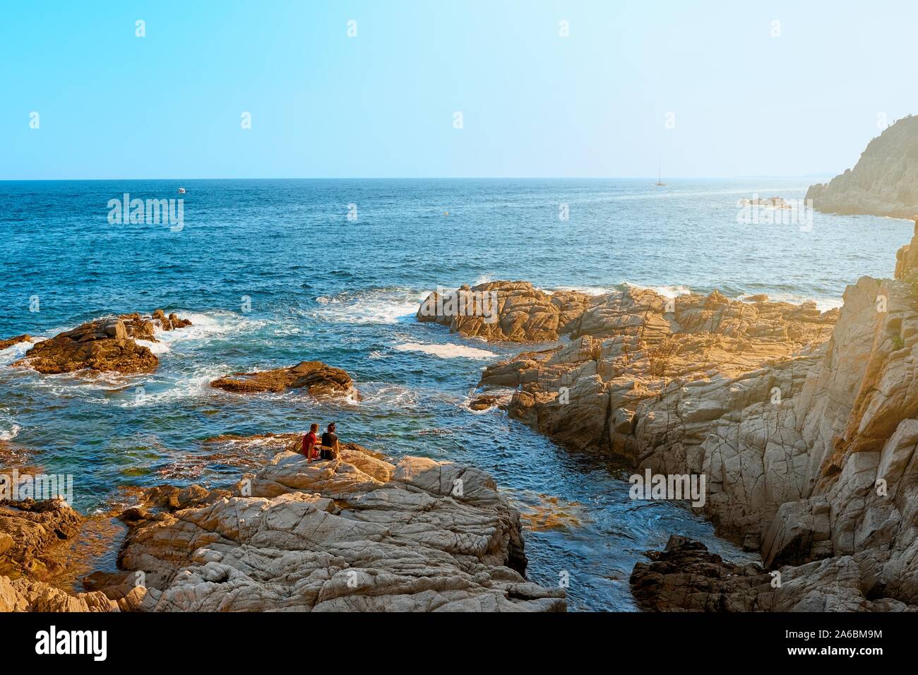 Mer. Jeune couple sur une côte rocheuse au coucher du soleil. Paysage d'été romantique. Banque D'Images