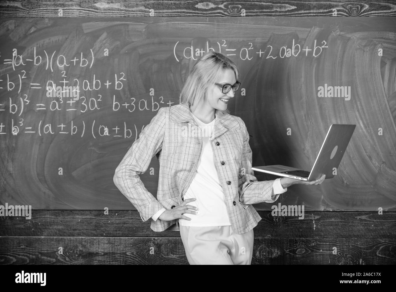 L'éducation scolaire de base. Dame élégante avec des enseignants pour ordinateur portable moderne tableau internet surf arrière-plan. Concept de formation à distance. Enseignante portent des lunettes est titulaire d'ordinateur portable Internet surf. Banque D'Images