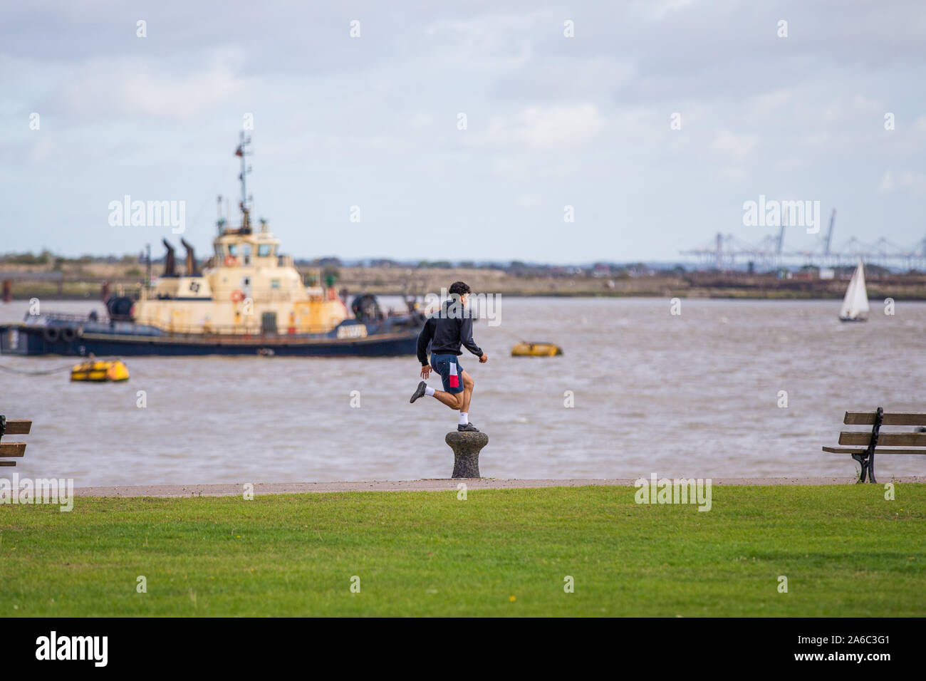 Un homme courir et sauter sur un poteau le long de la Tamise à Gravesend, Kent. UK Banque D'Images