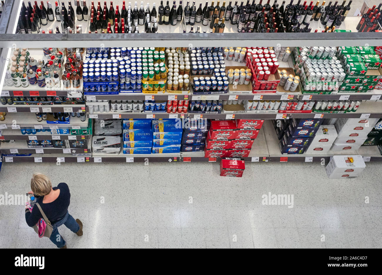 Regardant vers le bas sur l'allée des boissons au supermarché Sainsbury's, à Gloucester avec une femme le choix de bières qui à acheter Banque D'Images