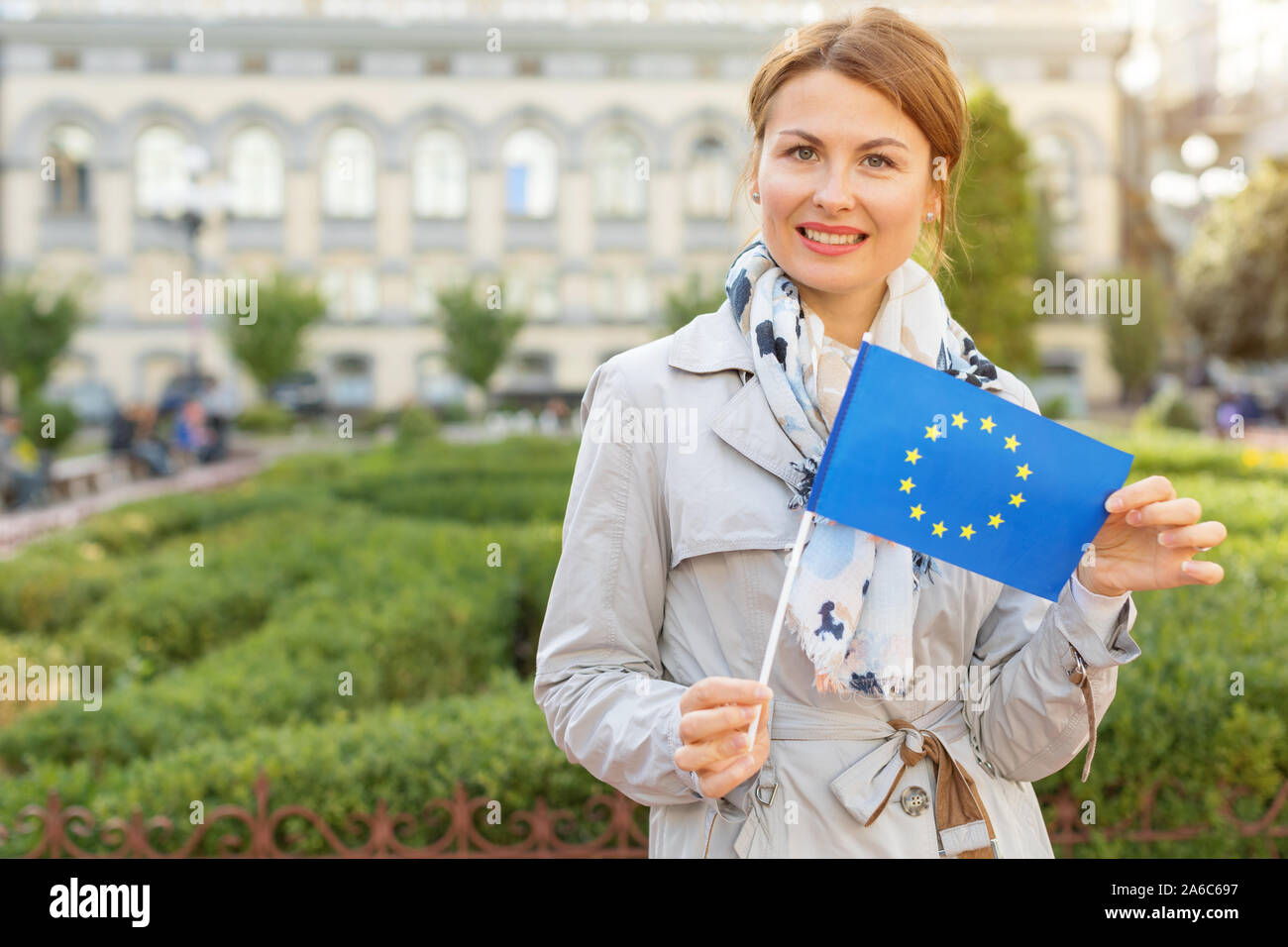 Femme d'âge moyen avec le drapeau de l'Union européenne, sur un arrière-plan du parc et de la ville. Banque D'Images