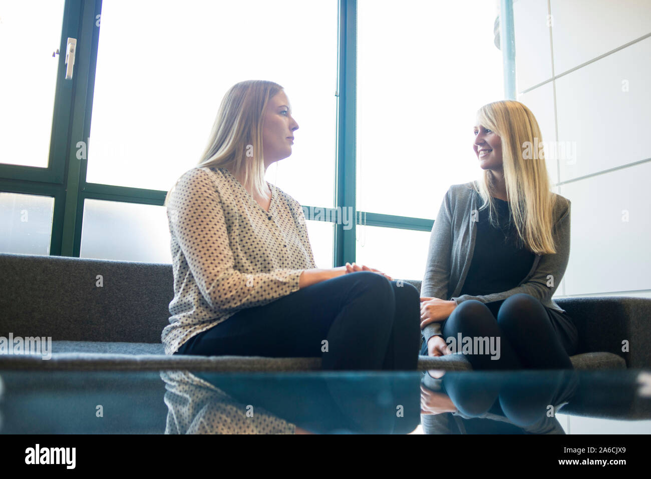 Deux femmes s'asseoir à la réception en attendant le chat sur un canapé Banque D'Images