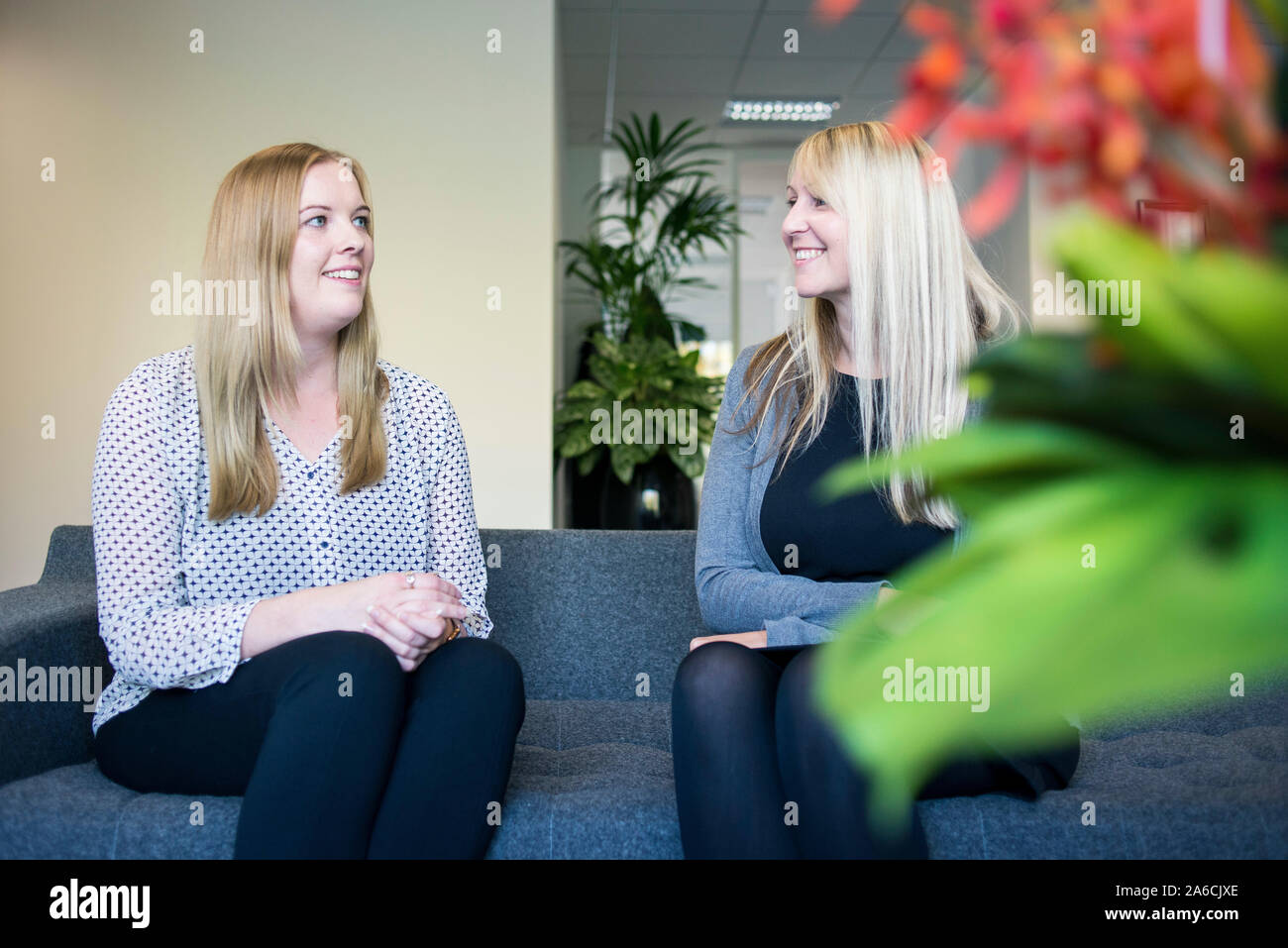 Deux femmes s'asseoir à la réception en attendant le chat sur un canapé Banque D'Images