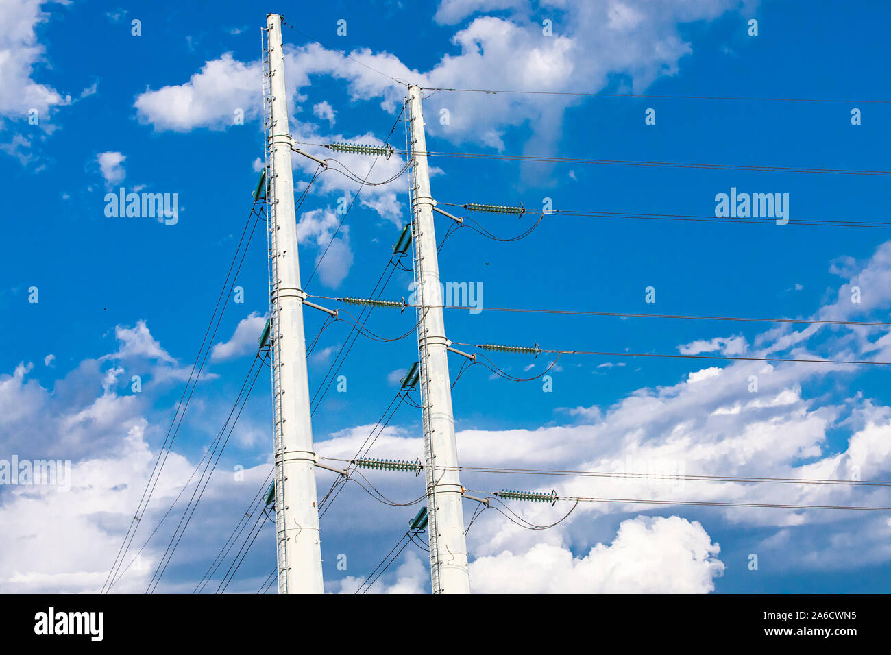 Un low angle view of twin les poteaux électriques moyenne tension des fils à l'aide d'isolants et d'échelles d'accès pour l'entretien, services publics urbains d'infrastructures. Banque D'Images
