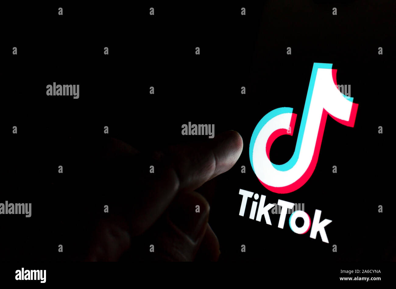 TikTok app logo sur l'écran et un doigt sur le point de le toucher. Banque D'Images