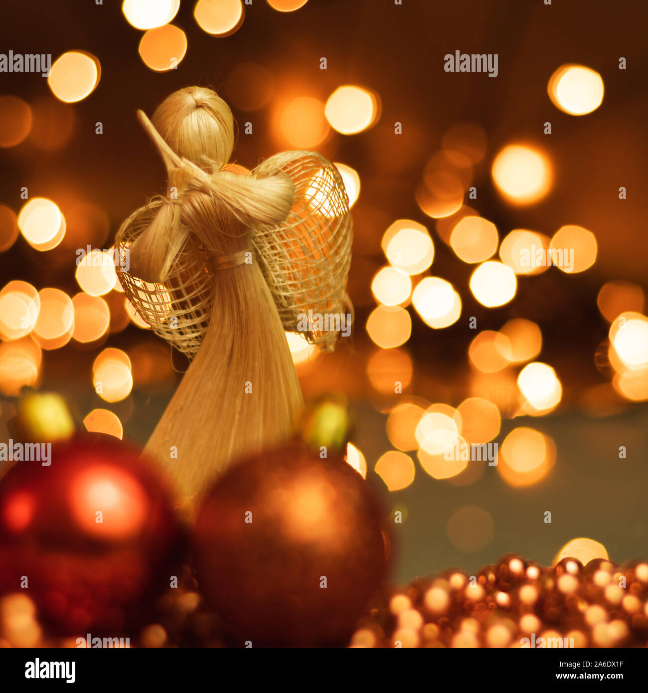 Ornements de Noël et la paille ange couché sur une chaîne de boules de Noël sur un arrière-plan flou avec des lumières. Banque D'Images