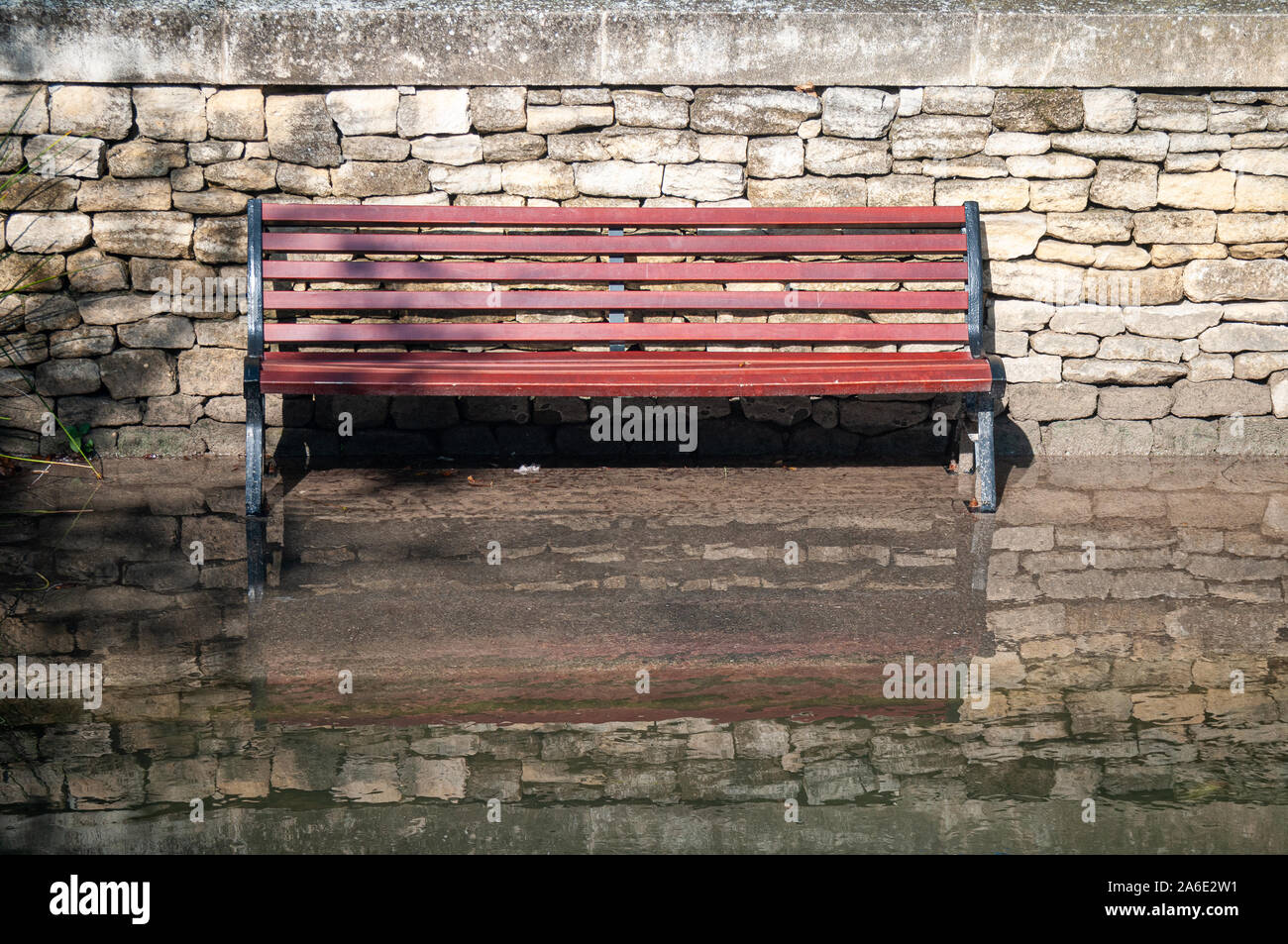 Banc de parc avec ses pieds dans l'eau et de réflexion contre un mur de pierre, effets du réchauffement climatique et la montée du niveau de l'eau. Vaucluse.France Banque D'Images