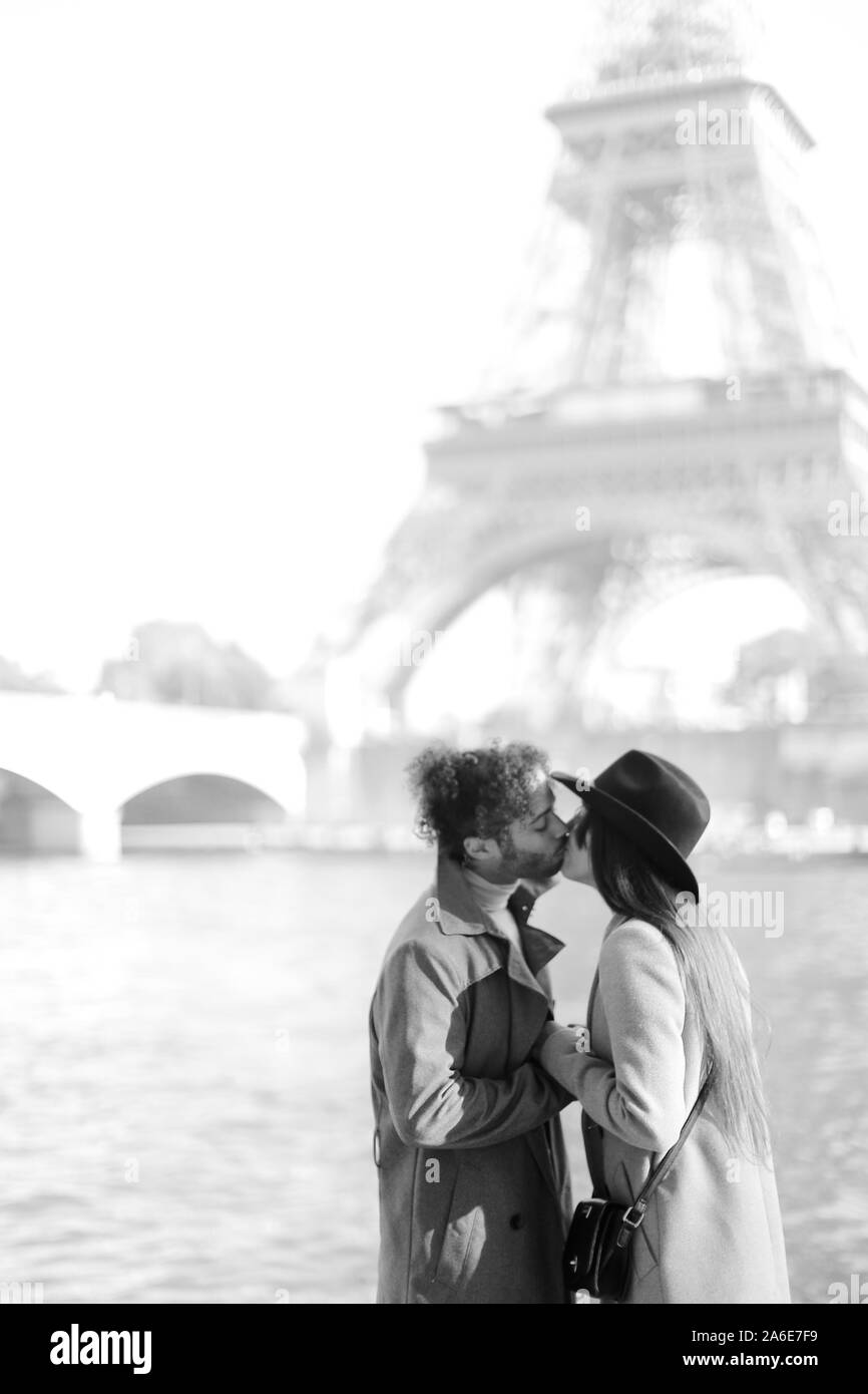 South American boy kissing girl in hat près de Eiffel Tower, Paris. Banque D'Images