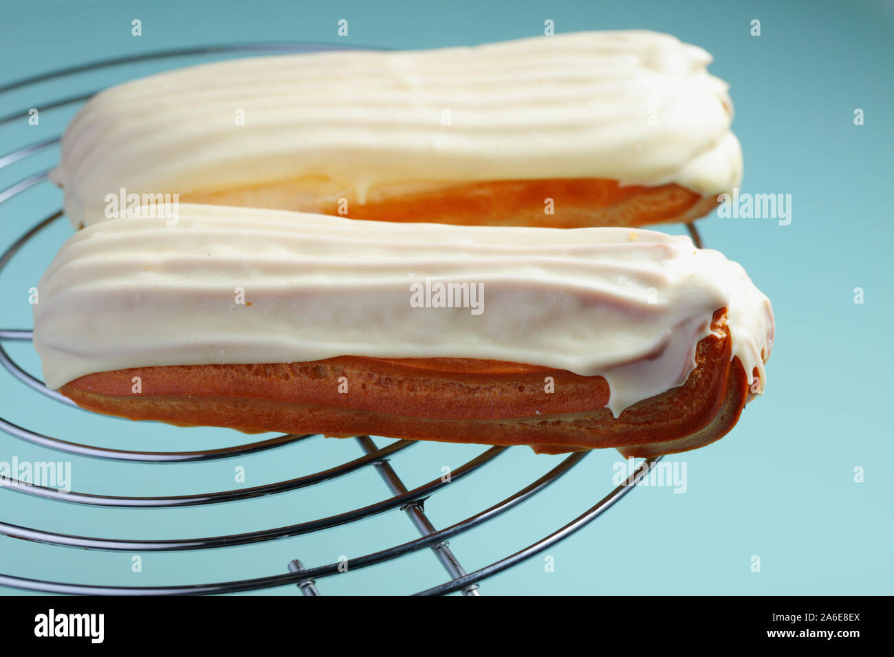 Éclairs au chocolat blanc glace contre des oeufs de canard fond bleu. Les couleurs pastel et copyspace Banque D'Images