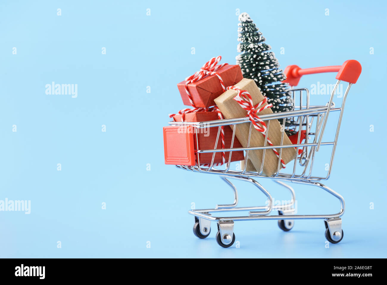 Panier plein de cadeaux divers et un arbre de Noël sur fond bleu clair. Vente de Noël concept. Banque D'Images