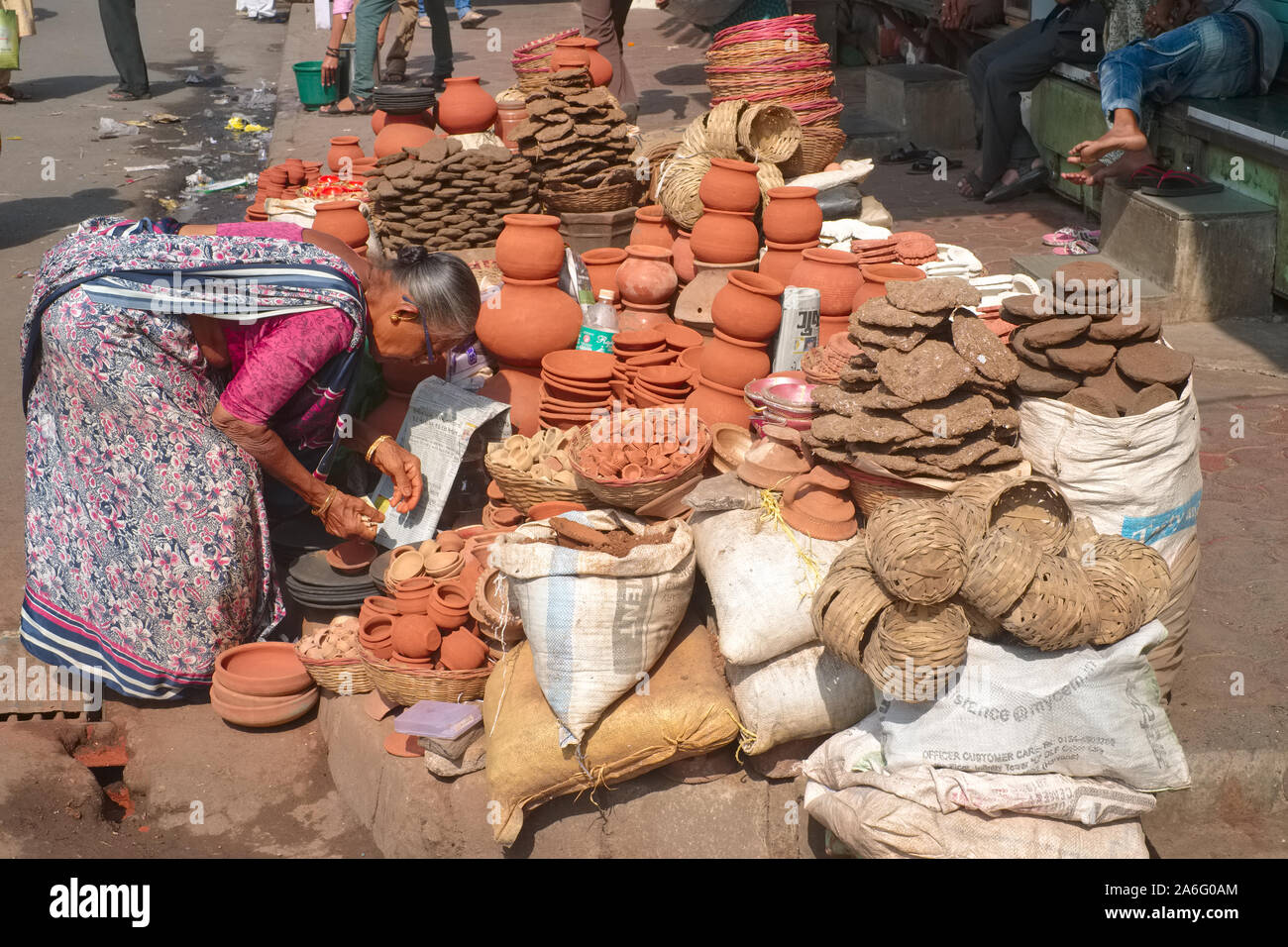 Un vendeur à son étal dans Bhuleshwar, Mumbai, Inde, la vente d'articles de poterie et de bouse de vache séchée gâteaux, ce dernier utilisé comme offrandes dans les temples hindous d'incendie Banque D'Images