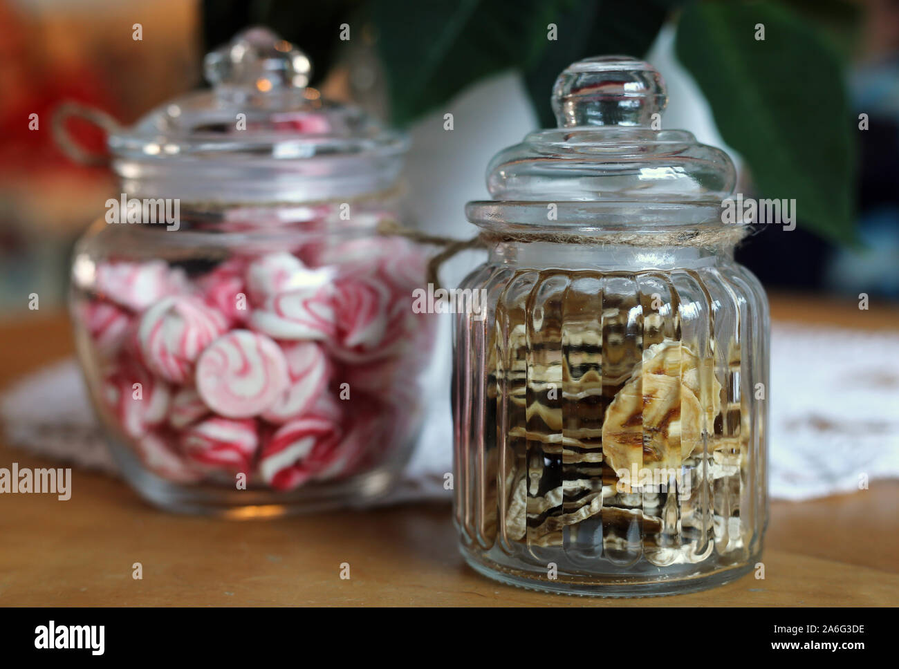 Deux pots en verre comprenant des rouge et blanc meringues en spirale et bananes frites sur une table en bois. Sweet gourmandises pour Noël. Belle ! Banque D'Images