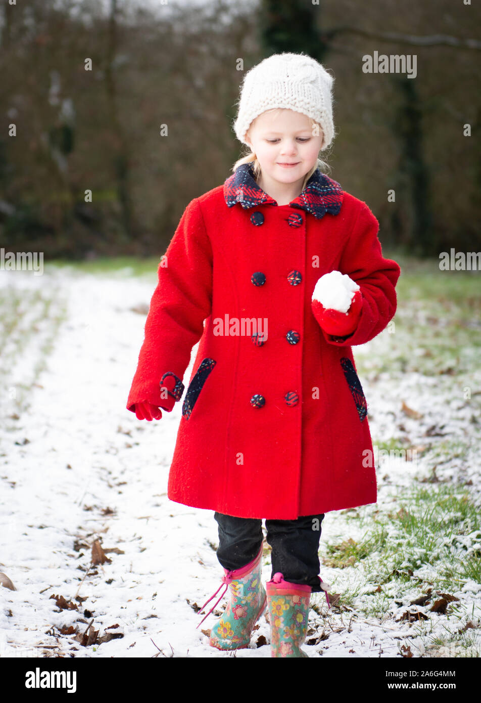 Une magnifique petite fille portant un manteau rouge et wooly hat jouer  dans la neige sur une froide journée hivers à Noël, veille de Noël,  Trentham Gardens, Stoke Photo Stock - Alamy