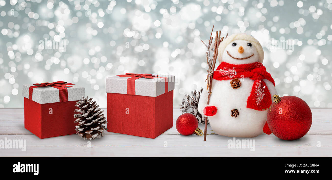 Bonhomme de neige, cadeaux, ballons et les cônes sur table en bois blanc. Bokeh lights en arrière-plan. Noël, Nouvel An composition, close-up. Banque D'Images