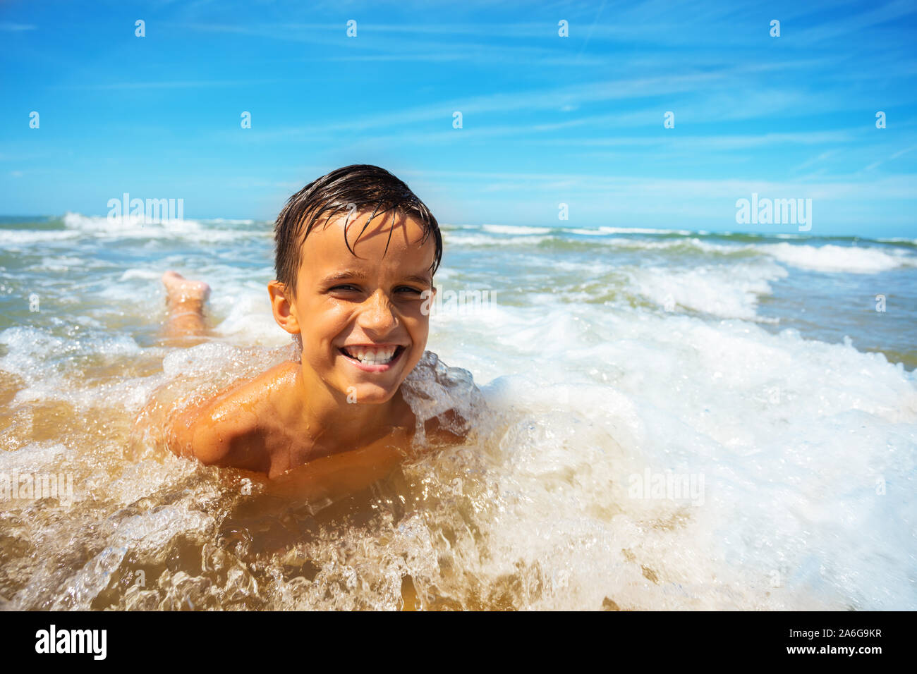 Happy smiling boy jouer dans les vagues de la mer sur une plage Banque D'Images