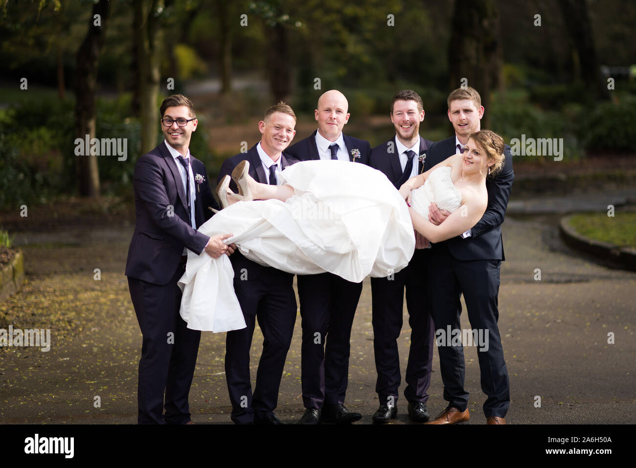 Un groom et ses meilleurs hommes tenir la bride dans l'air pour une photo amusante sur un jour de mariage Banque D'Images