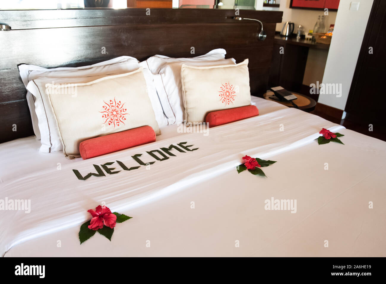 Grand lit avec oreillers et une couverture blanche, décoré avec des fleurs tropicales et une inscription - bienvenue. Thème de l'hôtel service, hôtel, plage, reste Banque D'Images