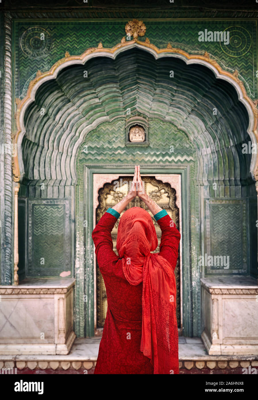 Femme indienne en écharpe rouge avec mains en prière au geste green gate porte, dans les palais de la ville de Jaipur, Rajasthan, Inde. L'espace pour votre texte, peut être utilisée à Banque D'Images