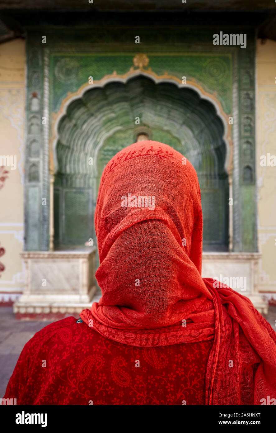 Femme indienne en écharpe rouge à la porte à porte verte dans la région de palais de la ville de Jaipur, Rajasthan, Inde. L'espace pour votre texte, peut être utilisé comme livre ou magazine Banque D'Images