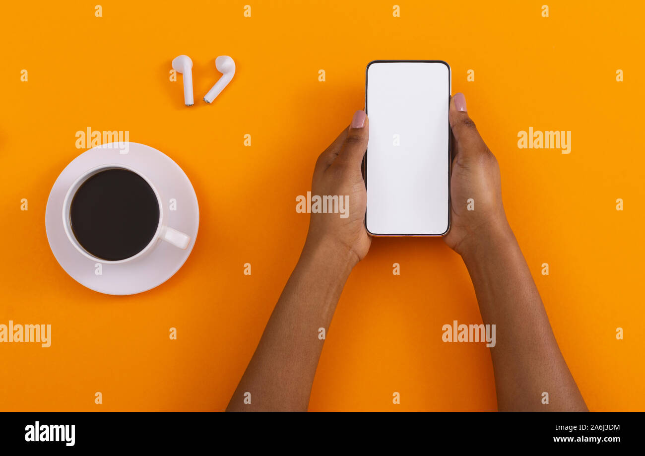 Smartphone avec écran blanc, café et écouteurs sur fond orange Banque D'Images