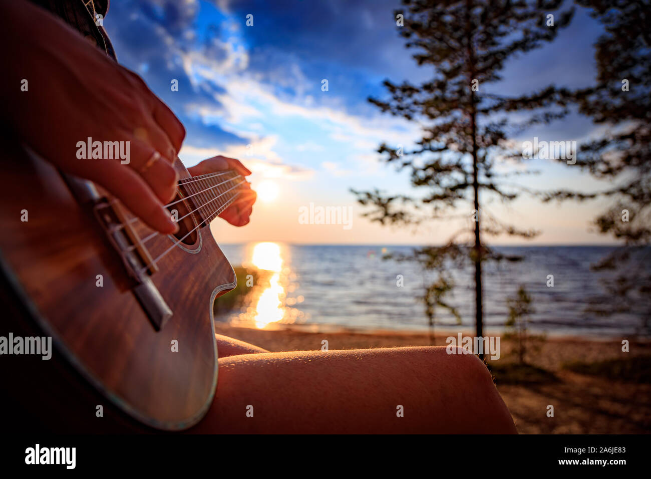 Femme au coucher du soleil tenant un ukulele Banque D'Images