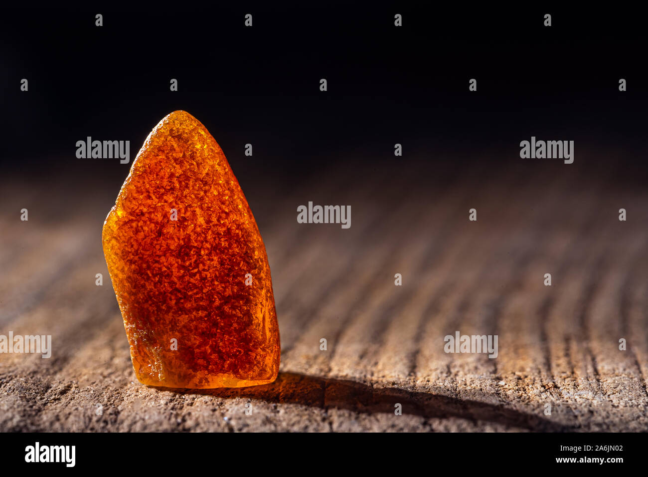 L'ambre naturel. Un morceau d'ambre naturel transparent jaune sur un grand morceau de bois de pierres sombres. Banque D'Images