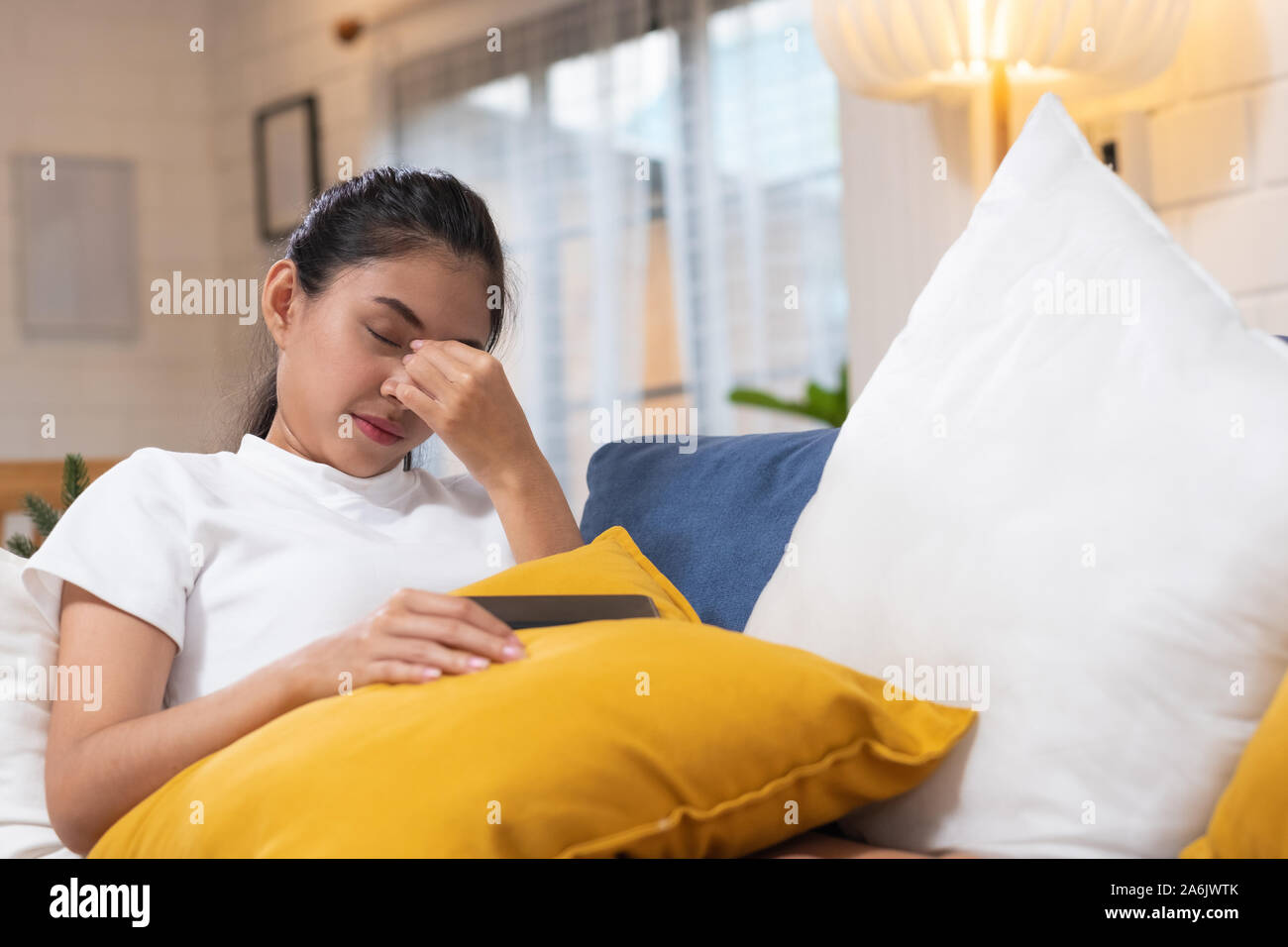 Young Asian woman sentiment de stress et fermé les yeux souffrant de maux de tête et couché sur un canapé dans la salle de séjour,fatigué female office worker massagin Banque D'Images